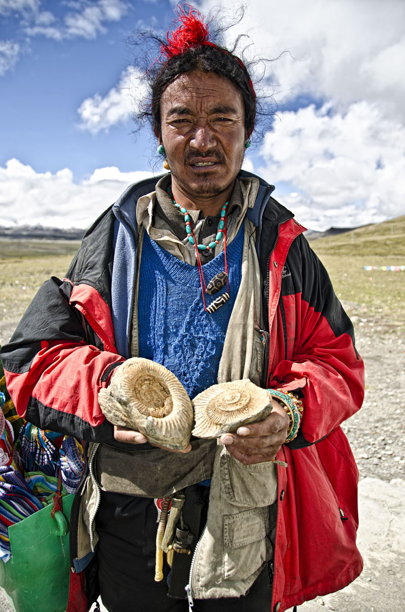 Ancient wisdom Tibetan man offering fossils for sale atop, Tropou La (4500 m; 14,763 ft). Before the collision with the Indian subcontinent, Tibet was a sea, and marine fossils are thus found throughout the land. Photo: Richard W. Hughes