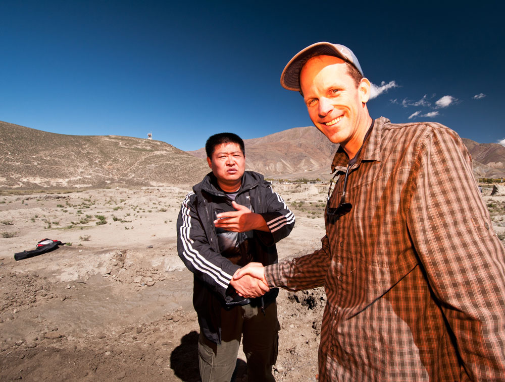 Figure 11. Liberation Day Li Tong and Brendan Laurs shortly after we found andesine beneath a randomly chosen bush. Li Tong has worked for years to show the world that Tibetan andesine is real. Photo: Richard W. Hughes